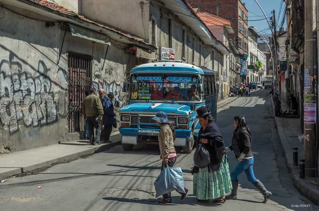 Traditionally dressed women crossing a street front of a bus at 